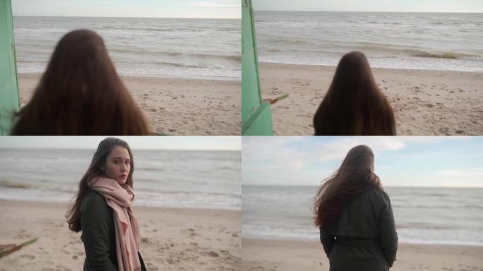 悲伤的沉思的混合民族妇女走下楼梯到沙滩，转身，看着镜头离开。风吹动体贴女性的长发。海浪在海边。