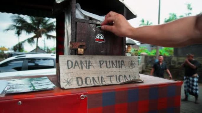 站在印度尼西亚寺庙前的桌子上的木制捐款箱