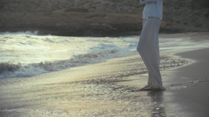 独自站在海滩上的女人。望着遥远的大海，赤脚感受沙子