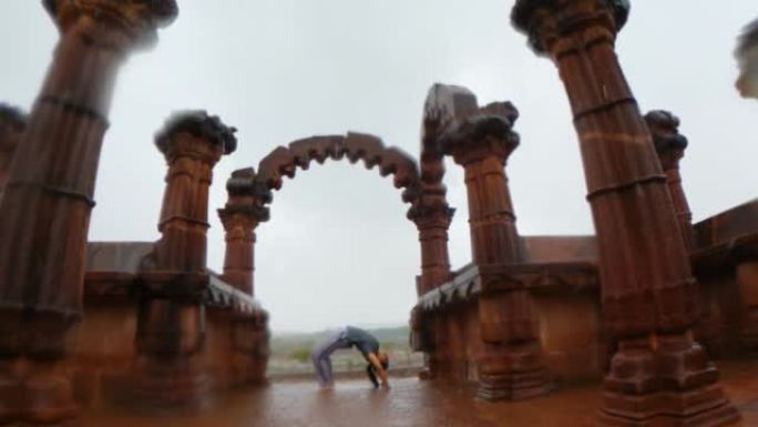 印度古吉拉特邦布吉下雨时，年轻的印度妇女在古老的历史建筑Chhatardi的柱子之间表演Chakra