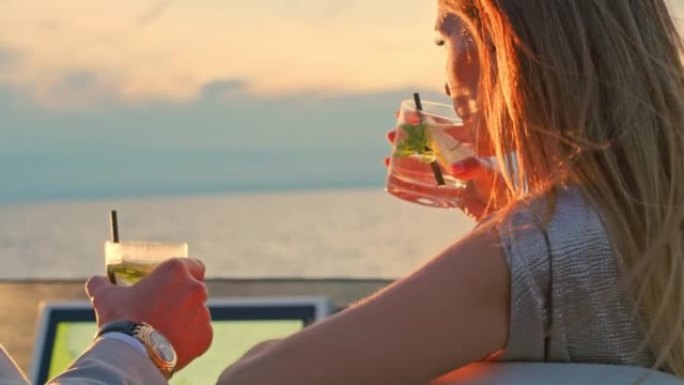 日落时在游艇桥上享受鸡尾酒的SLO MO男人和女人