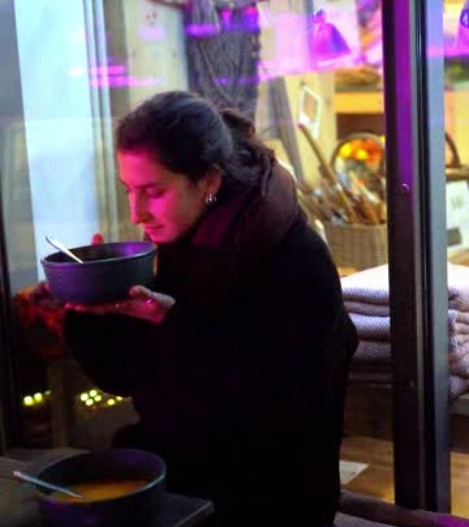 年轻女子在有机商店外面吃一碗热腾腾的食物
