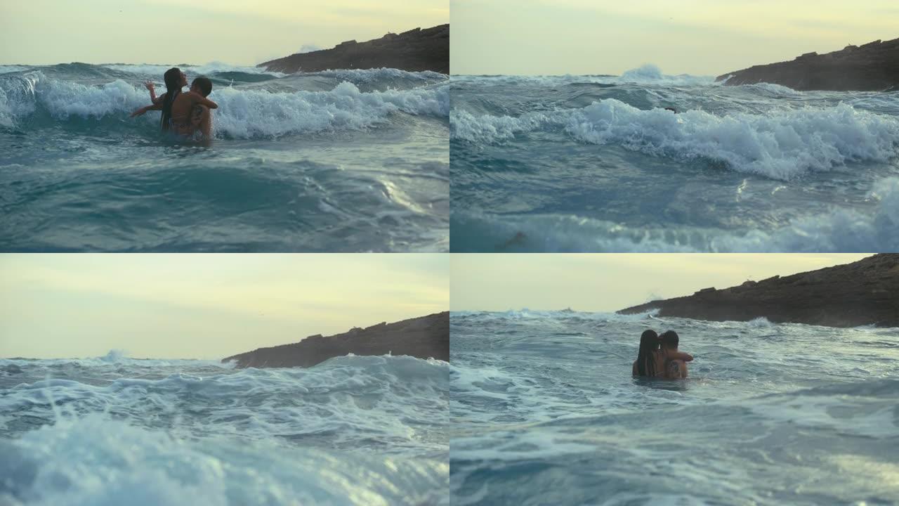 海滩上的浪漫情侣。在海中玩耍，在海浪中游泳，拥抱