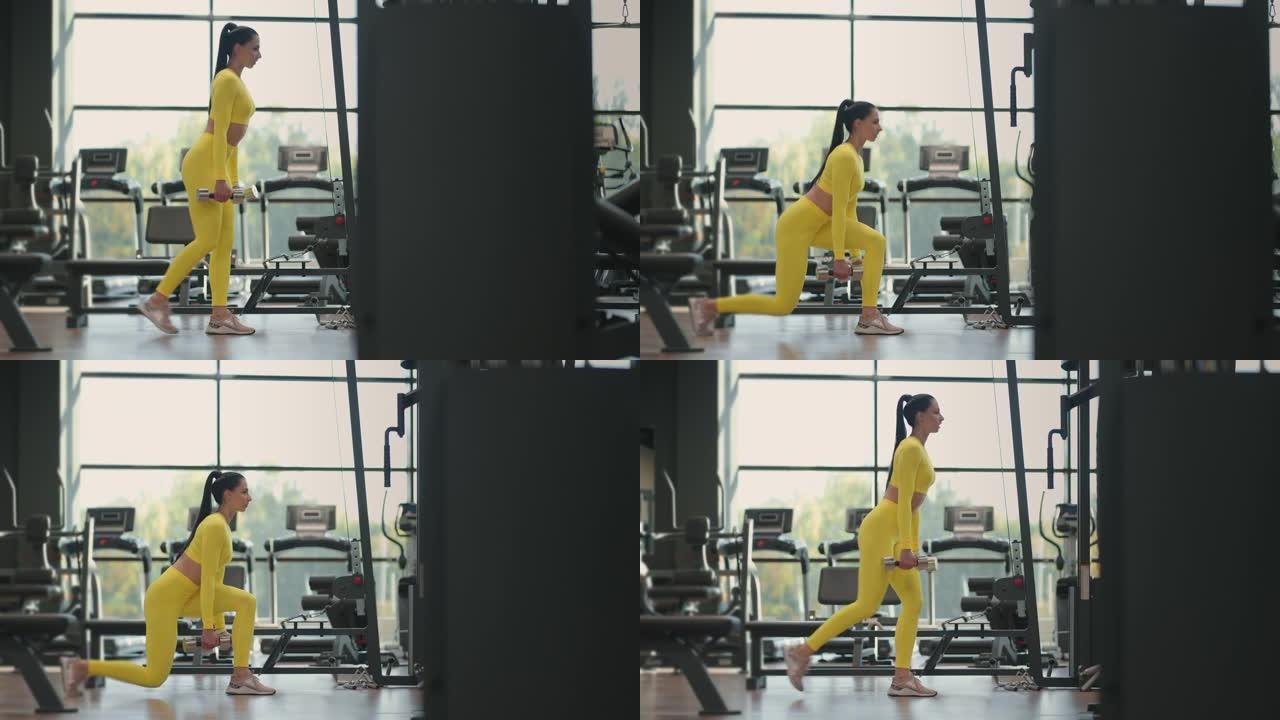 年轻肌肉发达的西班牙裔女性穿着黄色运动服在健身房用哑铃做弓步运动。女运动员在健身房的弓步姿势用哑铃锻