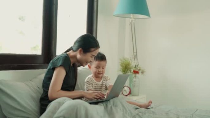 亚洲母亲和她的儿子在家里使用笔记本电脑。