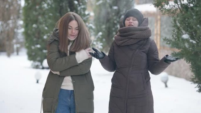 被冻结的女人摩擦手，跳舞，作为快乐放松的朋友在户外享受冬天的天气，热身。多样性和友谊概念。