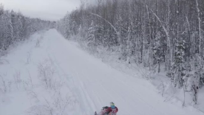 森林里的冬季之路。夹。一条积雪很多的道路，一个人在冰杉树旁骑着电动雪猫