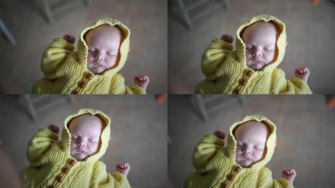 刚出生的婴儿穿着黄色手工毛衣睡在母亲的手中