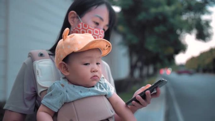 亚洲妇女和儿子晚上在城市街道上用智能手机发短信