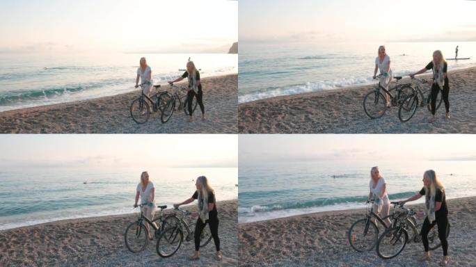 两名高级妇女沿着海滩推自行车