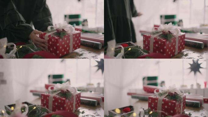 一名年轻女子用花环在木桌上装饰礼物，翻过来放在桌子上，用慢动作的丝带压碎了现成的圣诞盒