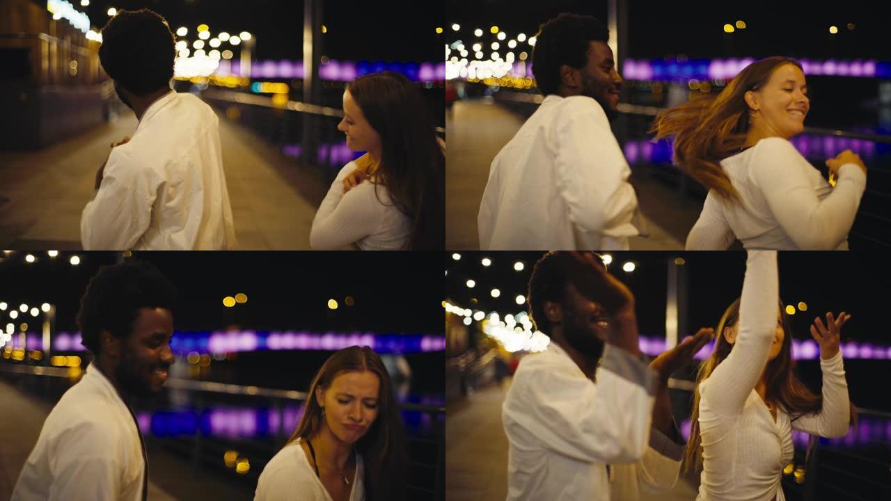 年轻多样的夫妇在潮湿的城市街道上表演现代舞蹈。开心和微笑。夜景在河中反射