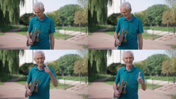 在夏季春季公园，自信英俊的积极的高级男子指着拇指微笑着看着摄像机站在滑板上的肖像。适合白人退休人员在