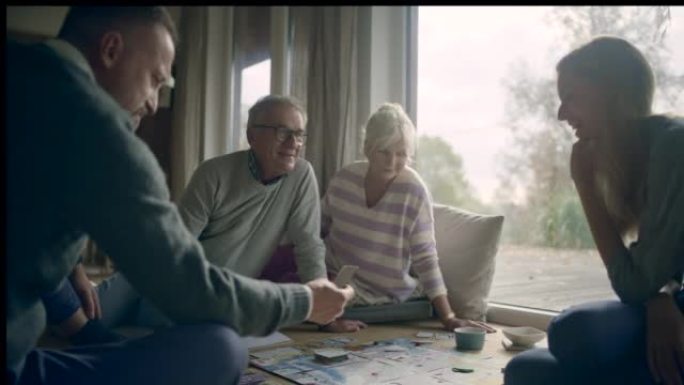 年轻的已婚夫妇与年迈的祖父母一起在桌子上玩棋盘游戏