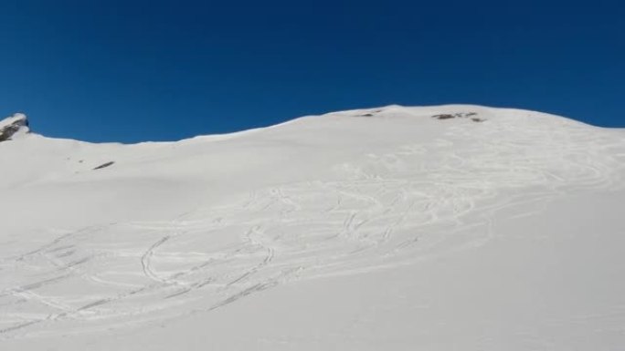 在阳光明媚的日子里，滑雪者从白雪皑皑的山腰下降的第一人称视角