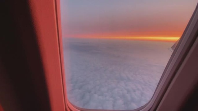 从飞机窗户看到云层上方令人惊叹的日落的第一人称视角
