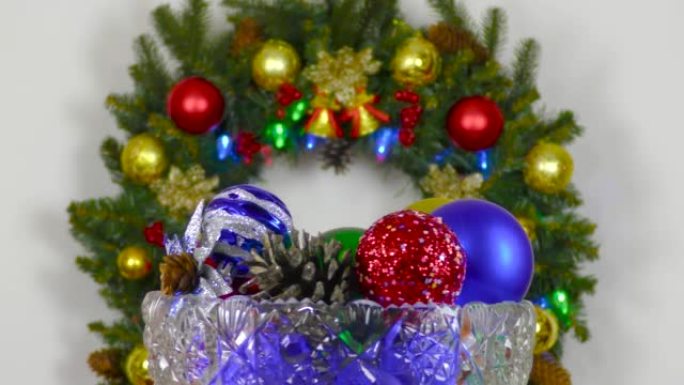 在圣诞节花环的背景下，中间装有彩球的花瓶旋转