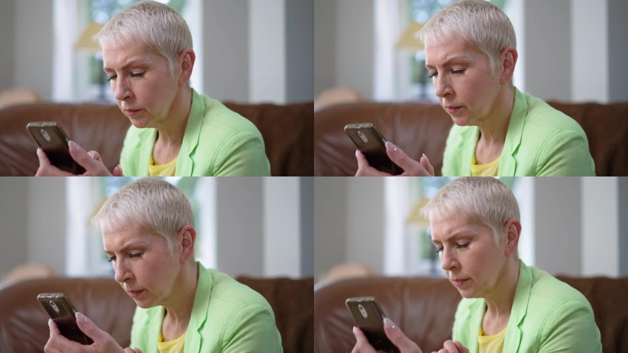 中年妇女斜视着慢动作看着智能手机屏幕。白人白发女商人的肖像，视力不佳，在电话应用程序中阅读在线消息。