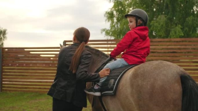 大自然中的儿童骑马散步，女子骑马教练正在带领小马，背上有小男孩