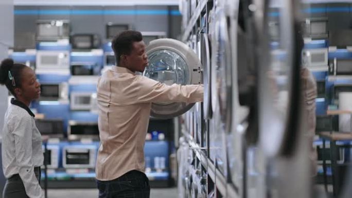 美国黑人配偶在家电商店购物，年轻男女在五金店看洗衣机