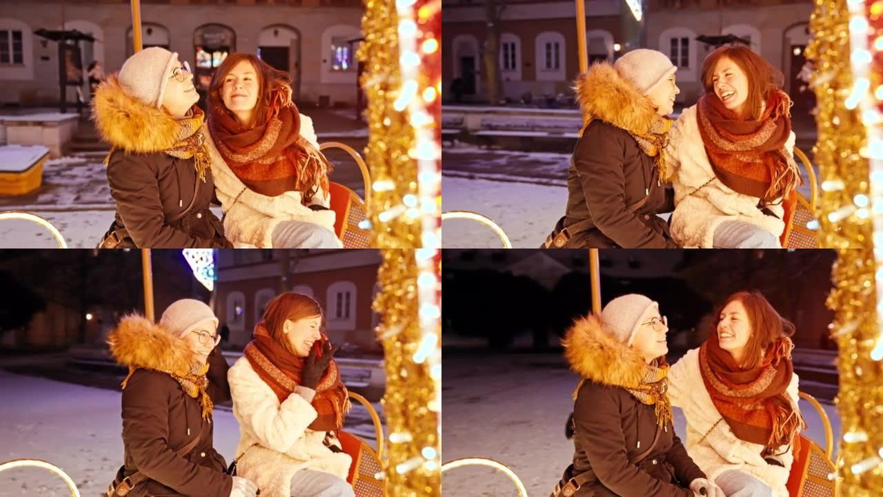两个女性朋友在下雪的圣诞节夜晚一起慢动作旋转木马