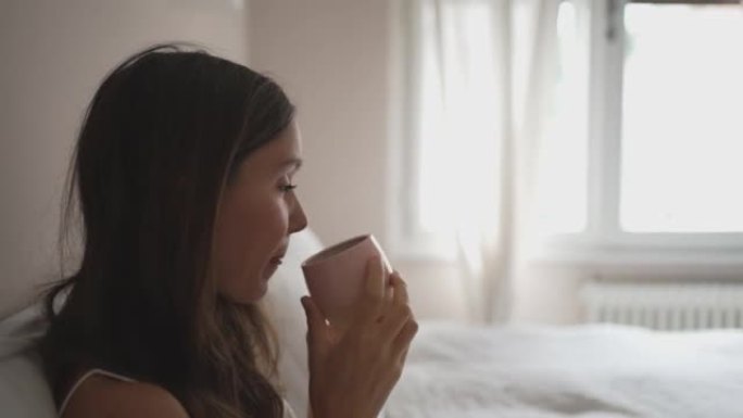 年轻女子在床上喝咖啡