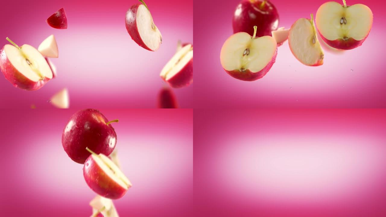 粉红色背景下的红苹果和切片的飞行