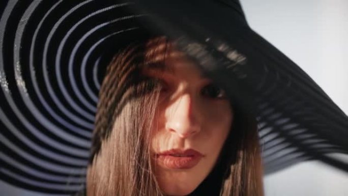美丽诱人的黑发女人用相机调情。戴着大而优雅的帽子和红色唇膏摆姿势