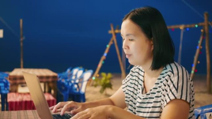 自由职业者在海滩上旅行时使用笔记本电脑。