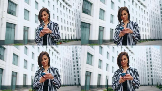 有魅力的女人在智能手机上输入短信，城市景观中成功女士的肖像