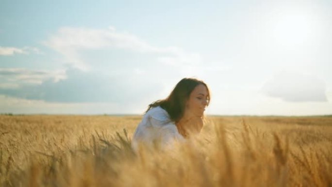 在阳光明媚的夏日里，性感的年轻女子抚摸着农田里金黄的麦穗，幸福快乐