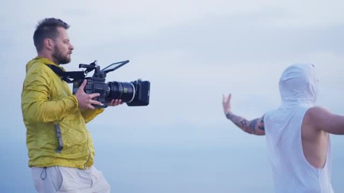 男人带着相机在山顶上拍摄电影