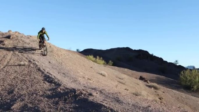 一名男性山地自行车手正从岩石嶙峋的沙漠小路上滑下