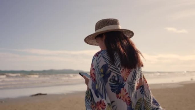 日落时分，亚洲女子在海滩上玩智能手机。