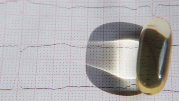 ECG背景上的omega-3胶囊特写滚动。健康心脏概念。