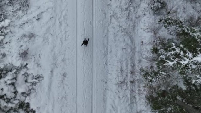 空中无人机拍摄了一名妇女在树林中沿雪道行走的镜头