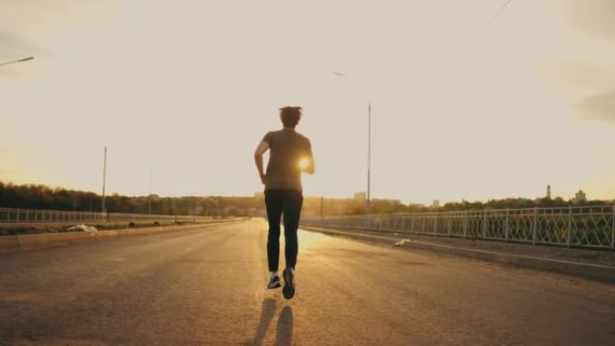 年轻的运动员在夏天的早晨或晚上独自跑步，男性慢跑者的后视
