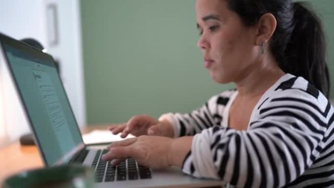 侏儒症妇女在家里学习或工作时使用笔记本电脑