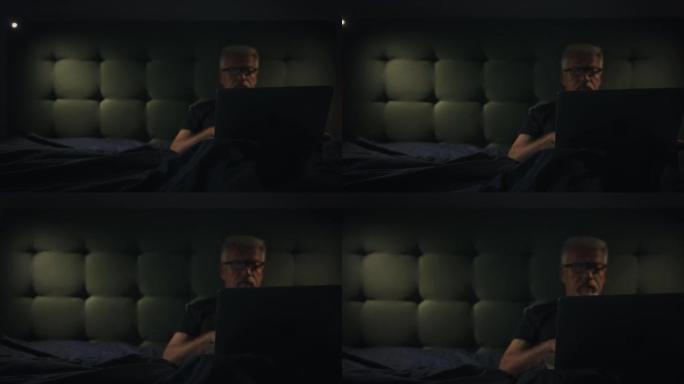 躺在床上的男人因失眠而无法入睡。使用笔记本电脑