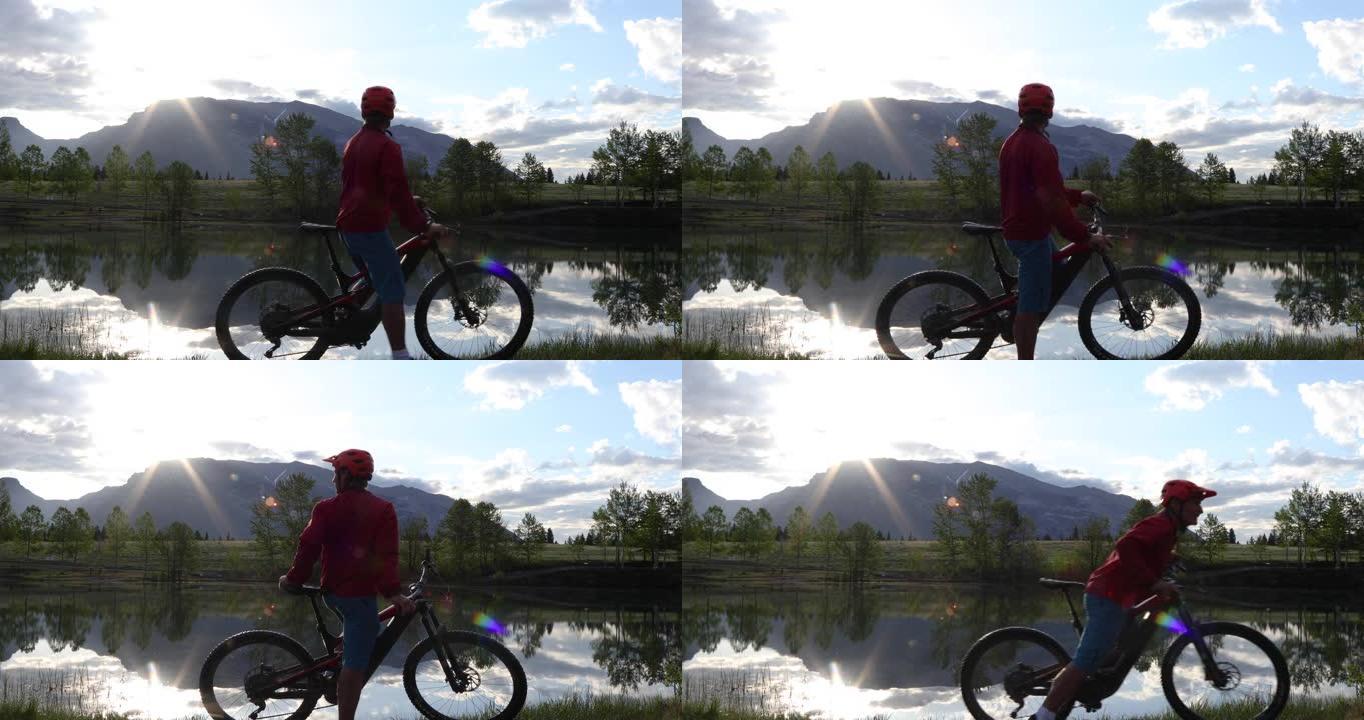 日出时，男子在山湖边缘骑自行车