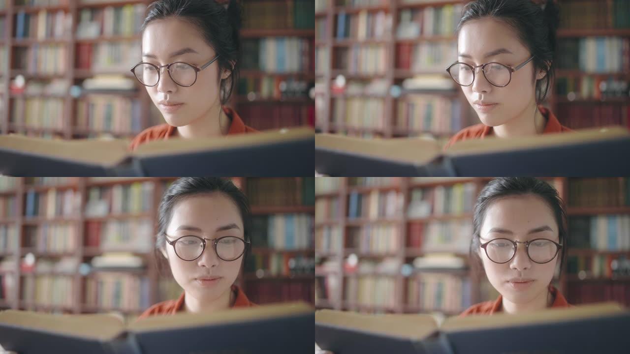 穿着眼镜的美丽亚洲女人在大学图书馆读有趣的书