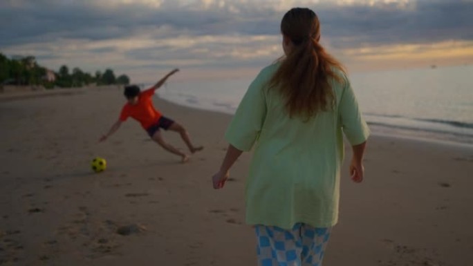 慢动作: 夫妇在海滩日落时踢球