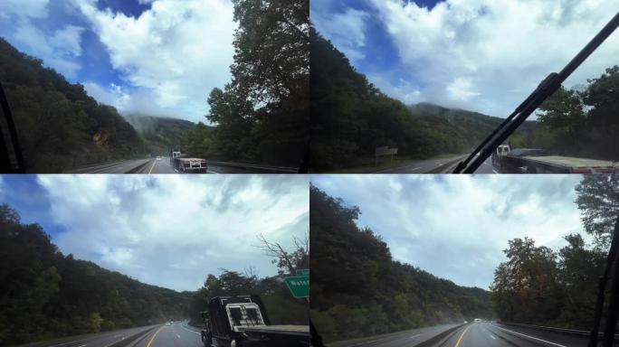 在戏剧性的多云天空下，沿着田纳西州蓝岭山脉40号州际公路树木弯曲的路段行驶的雨中，汽车的视角通过挡风