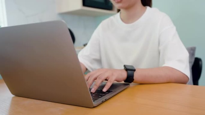 4K，特写，手，亚洲女人穿着白色t恤，手打键盘，在笔记本电脑键盘上，他在一台电脑上在家工作，手正在快