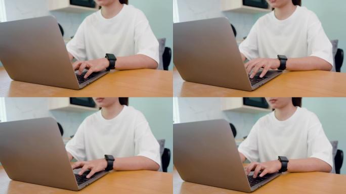 4K，特写，手，亚洲女人穿着白色t恤，手打键盘，在笔记本电脑键盘上，他在一台电脑上在家工作，手正在快
