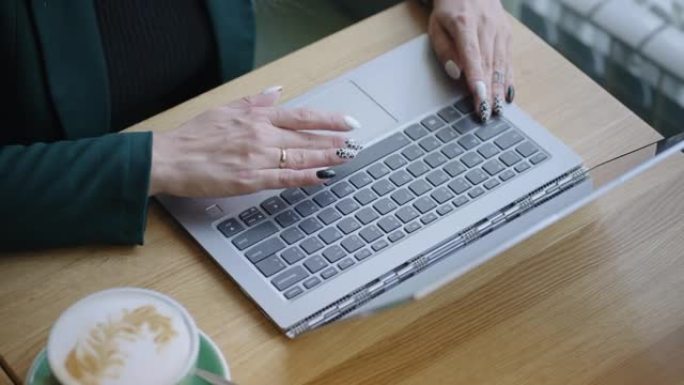 女人正在笔记本电脑的键盘上打字，手和工作台的特写镜头，上网