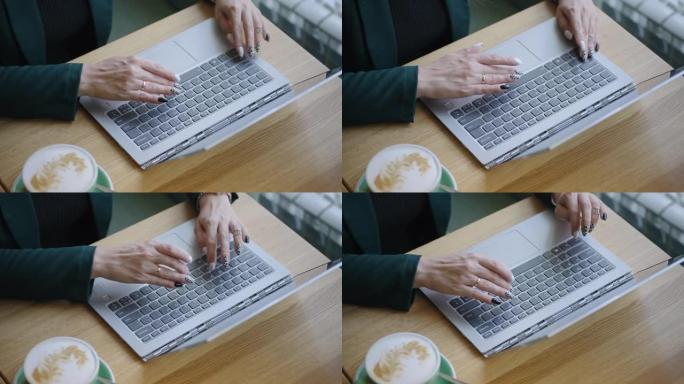 女人正在笔记本电脑的键盘上打字，手和工作台的特写镜头，上网