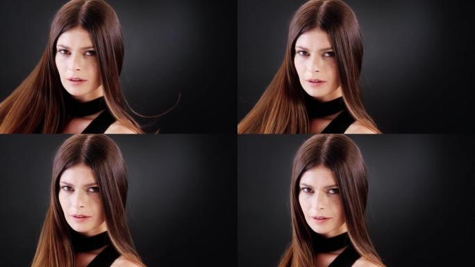 美丽的黑发女人扔掉她的长发。看着相机和调情