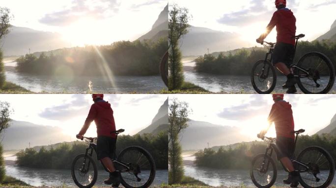 男性骑自行车的人在黎明时沿着山河上方的轨道前进