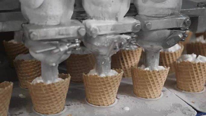 机器人机器会自动将冰淇淋倒入威化饼杯中。用于生产冰淇淋蛋筒的输送机自动线。威化杯和圆锥体。大型工业生